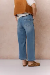 Pantalón de jean con corte wide crop y tiro alto. Presenta un lavado azul clásico con sutiles desgastes, pierna amplia con largo al tobillo, cierre frontal con botón y bolsillos funcionales.