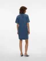 Vestido corto de denim en tono celeste claro, con cuello camisero, cierre frontal con botones metálicos, bolsillos con solapa en el pecho y mangas cortas con vuelta.
