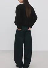 Blusa de algodón negra con detalles florales bordados, cuello en pico con cierre de lazo, manga larga abullonada y diseño recto con vuelo en la cintura.