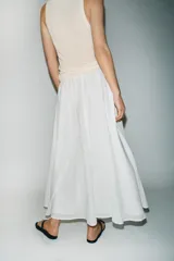 Falda midi de corte en A, color blanco, confeccionada en algodón con cintura elástica de tiro alto y forro interior a tono.