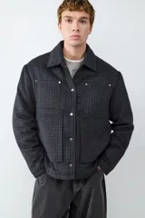 Campera de paño con diseño a cuadros, cuello clásico, cierre frontal con botones metálicos y bolsillos frontales tipo parche.