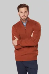 Buzo de lana color terracota con cuello alto y cierre frontal parcial. Presenta puños y ruedo acanalados, con detalle de logo bordado en el pecho y tirador de cierre en cuero.