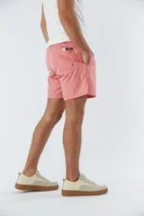 Short de baño liso color salmón, con cintura elástica ajustable mediante cordón, dos bolsillos laterales y un bolsillo posterior.