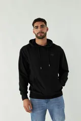 Buzo de felpa negro con capucha, cordones ajustables y bolsillo tipo canguro. Tiene puños y cintura acanalados, y logo en grifa de plástico.