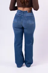 Jean de corte wide leg con tiro alto, confeccionado en denim de color azul medio. Presenta diseño de cinco bolsillos, cierre frontal con botón y cremallera, y pernera amplia y recta.