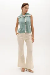 Chaleco de punto sin mangas, color azul marino, con cuello y frente adornados con volados en contraste de color blanco o crudo.