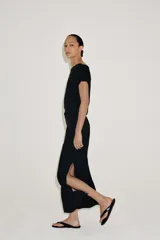 Vestido midi negro confeccionado en hilatura de viscosa, de diseño satinado y corte asimétrico con escote fluido y manga sisa. Presenta bajo acabado en línea evasé y cierre lateral con cremallera oculta en costura.