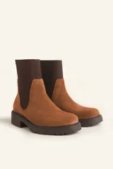 Bota tipo chelsea de gamuza color marrón, con paneles laterales elásticos acanalados y suela de goma track con taco bajo.