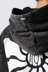 Buzo canguro con capucha, de calce oversize y efecto lavado gastado. Presenta un estampado gráfico central en color blanco y un pequeño parche con logo en el puño.