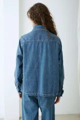 Campera de denim azul con múltiples bolsillos frontales con solapa, cierre frontal de botones metálicos y cuello camisero.