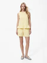 Top sin mangas de algodón orgánico y poliéster reciclado, color amarillo con estampado de cuadros vichy, cuello redondo y detalle de volado en el ruedo.