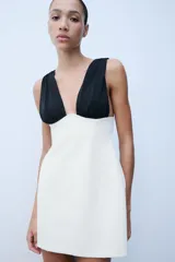 Vestido corto bicolor con cuerpo blanco y tirantes anchos negros plisados en contraste, de escote en pico y corte ajustado.