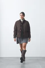 Campera tipo barn capitoneada de color marrón, con silueta corta y relajada. Presenta cuello de pana, cierre frontal con broches metálicos y bolsillos laterales funcionales.