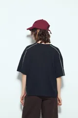 Remera negra de manga corta con estampado tipográfico "City of Angels California 1997" en tonos marrones y costuras visibles en blanco.