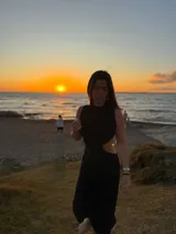 Vestido midi negro con cuello halter y aberturas laterales en la cintura.