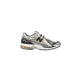 Championes New Balance modelo 1906R, color blanco con detalles plateados, negros y dorados, con diseño técnico de malla y superposiciones sintéticas, y tecnología de amortiguación N-ergy.