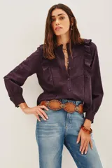 Camisa blanca de algodón con diseño romántico, cuello alto con volados, cierre frontal de botones y detalles de encaje y bordados calados. Presenta mangas largas con puños de encaje y volados frontales.