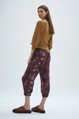 Babucha de corte relajado, con cintura elástica fruncida y puños anchos en el ruedo. Presenta un diseño estampado con motivos florales y botánicos en tonos bordó, azul y amarillo.