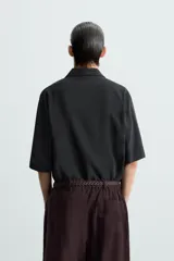 Camisa de corte relajado confeccionada en tejido con mezcla de modal, con cuello solapa, manga corta y cierre frontal de botones.