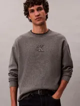 Sweater de punto Calvin Klein gris melange, con cuello redondo, manga larga y logo institucional "ck" en relieve en el centro del pecho. Corte regular.