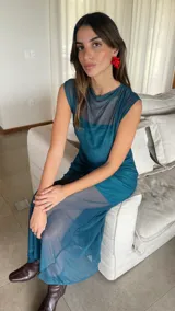 Vestido largo de microtul bordó, sin mangas, con escote alto tipo buche y diseño transparente con forro corto interno que genera un efecto translúcido en la falda.