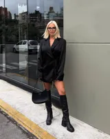 Vestido tipo blazer negro de corte entallado, con solapas clásicas, mangas largas y cierre frontal cruzado con lazo ajustable en la cintura.