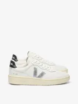Championes Veja modelo V-90, color blanco con detalles en plateado y negro. Presentan el logo de la marca en el lateral, puntera perforada y suela de goma en tono crema.