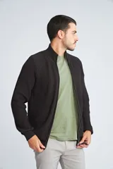 Campera tejida de algodón con cierre frontal completo, cuello alto y mangas largas con puños acanalados. Presenta un diseño de punto acanalado vertical y un pequeño logo bordado en el ruedo.