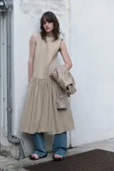 Vestido midi sin mangas de cuello redondo, con falda amplia con frunces y bolsillos laterales ocultos. Presenta cierre en la espalda con abertura y botón.