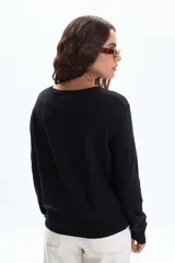 Saco de punto básico color negro, con cuello redondo y cierre frontal de botones dorados.