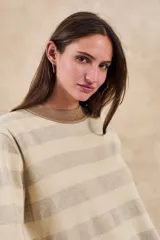Sweater de punto color beige melange con rayas horizontales en tono dorado brillante. Presenta cuello redondo y puños y ruedo en color marrón.