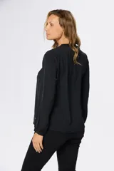 Blusa de manga larga en color azul marino, con escote en V y diseño de doble capa en el frente. Presenta puños elásticos y un pequeño aplique metálico decorativo en el ruedo.