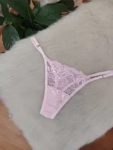 Microtanga de encaje rosado con diseño de tiras laterales regulables y detalle de aplique brillante en el centro.