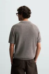 Polo de manga corta confeccionado en tejido de punto de algodón, con cuello solapa y cierre frontal de tres botones. Presenta terminaciones en rib en cuello, mangas y ruedo.