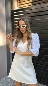 Vestido corto color crudo, con escote en V y mangas 3/4 abullonadas con detalles de calado.