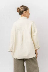 Sobrecamisa de gabardina liviana color crema, con corte oversize, cuello clásico, cierre frontal con botones a presión y dos bolsillos delanteros con solapa.
