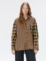 Camisa de manga larga con diseño estampado de rombos en tonos tierra, confeccionada en viscosa. Presenta cuello clásico, cierre frontal con botones, un bolsillo cuadrado en el pecho con logo bordado y puños a juego.