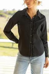 Camisa negra de manga larga con cuello clásico, cierre frontal con botones y volados verticales en el frente.