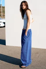 Pantalón cargo de tiro medio con corte oversize, bolsillos laterales con solapa en las piernas y bolsillos de plastrón en el delantero. Cuenta con trabillas, lazadas ajustables en la cintura y cierre frontal con cremallera y botón.