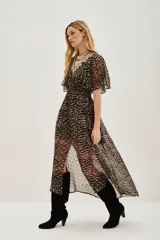 Vestido midi de tejido fluido con estampado en zigzag en tonos oscuros y dorados. Presenta un escote en V decorado con encaje, mangas cortas tipo mariposa, cintura elástica y una abertura frontal en la falda.