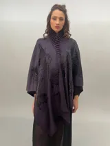 Ruana de lana merino tejida, teñida y estampada, con cuello plisado en fieltro de lana merino.