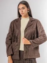 Chaqueta de estilo boho confeccionada en ecocuero agamuzado, con diseño de flecos en el frente, cierre frontal con botones y bolsillos laterales. Presenta un corte holgado y forro interior.