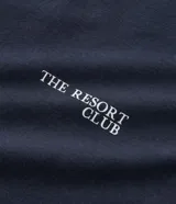 Remera azul marino de algodón con cuello redondo y manga corta. Estampa localizada en el frente con temática resort club y silla de playa.