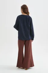 Blusa azul marino de viscosa, con cuello mao, escote con botones y frunces. Presenta mangas largas holgadas y detalles bordados al tono en el frente.