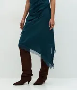 Pollera midi de satén color verde petróleo, con corte asimétrico y detalle de encaje aplicado en el ruedo. Presenta una cintura estructurada y una caída fluida.