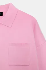 Sweater tipo polo de punto liso, con cuello solapa, manga larga y bolsillo delantero de plastrón. Presenta cierre frontal con botones y puños y ruedo acanalados.