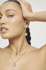 Aros colgantes de aleación de metales con baño de oro 18k, compuestos por un perno superior, una cadena de eslabones rectangulares y un dije inferior con forma de mariposa.