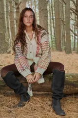 Saco de punto artesanal en color crudo, con diseño de red multicolor en mangas y laterales. Presenta cuello redondo, cierre frontal con botones y puños acanalados.