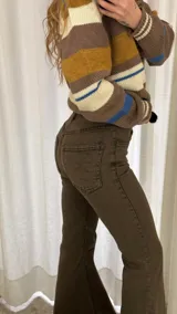 Jean acampanado color beige, de talle alto, con costuras visibles y terminación deshilachada en el bajo.