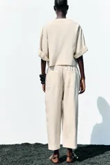 Chaqueta corta de escote en pico con cierre frontal de un botón. Presenta mangas cortas con detalle de vuelta, trabilla y botón, además de falsos bolsillos delanteros con solapa.